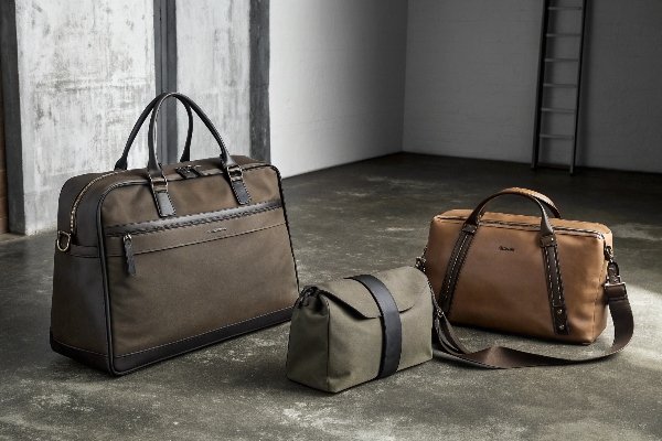 A stylish man in a city setting, carrying a sleek leather and canvas sling bag.