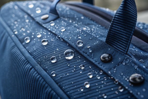 Water beading up and rolling off the surface of a treated waterproof corduroy bag.