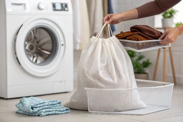 A corduroy bag placed inside a white mesh laundry bag next to a washing machine.